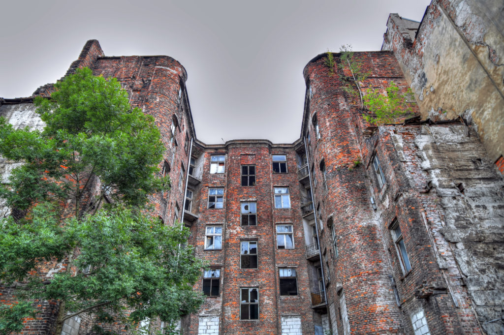 Facade of ruined old vintage red brick ghetto house at Kamienico part